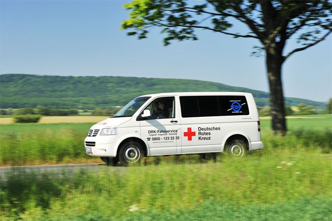 Foto: Ein Wagen des DRK-Fahrdienstes ist gerade auf der Landstraße unterwegs. Auf der linken Fahrzeugseite ist das Logo des Deutschen Roten Kreuzes schon aus der Ferne deutlich sichtbar.